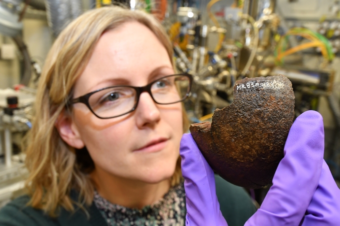 Professor Eleanor Schofield, Deputy CEO at the Mary Rose Trust, holding one of the retrieved cannonballs