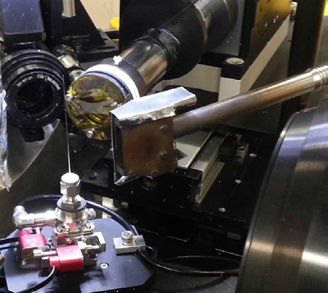 Figure 2: A capillary micro-reactor mounted on nano-positioning stages on I18 for chemical tomography of single particles. Surrounding the capillary (l-r) are an optical microscope, XRF detector, heater and XRD camera.