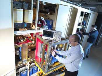 two members of the power supply team working on the transistors and capacitors of the booster supply